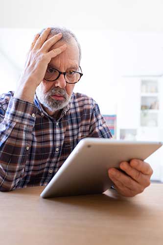 Senior man staring at his tablet with a worried look on his face