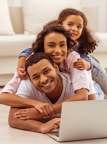 Young parents looking up life insurance on their laptop, with their little daughter