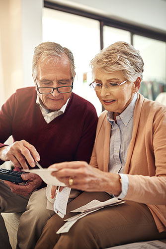 Senior couple working out a retirement budget while sitting on the living room sofa